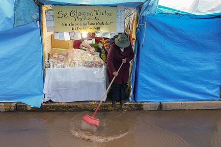 After the rain the seller tries to remove water from the booth front.  It looks like paddling on the boat. The sign says "your wish will come true"